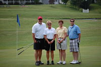 Picture of two males and two females standing on a golf course smiling. (Sandy Jones, Jeanine Ragain, Brad Ragain, and Andrew Darnell)