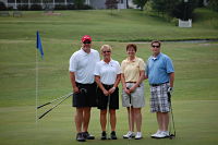 Picture of two males and two females standing on a golf course smiling. (Sandy Jones, Jeanine Ragain, Brad Ragain, and Andrew Darnell)