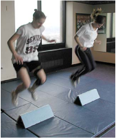Picture of two females jumping over an object during Sportsmetrics™ training.
