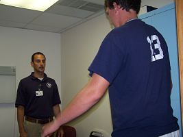 Picture of a man and student standing in a room. School sports physical clinics for area junior high and high school athletes.
