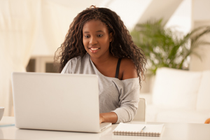 Picture of a female looking down at an open laptop.