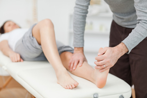 Picture of a woman lying down on her back while a Physical Therapist stretches her leg.