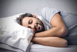 Picture of a man sleeping on a bed.