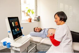 Picture of a patient lying down having  a FibroScan done by a female Nurse.