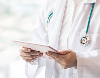 Picture of a Physician looking down at a smart tablet.