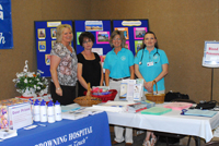 Picture of four females standing behind a table smiling.